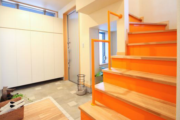 アクセントカラーにオレンジを用いた階段と玄関ホール